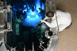 A reactor operator moves a sample in the reactor pool.