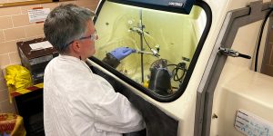 A researcher works in a glove box.