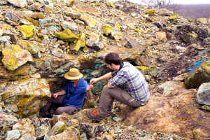 Two archaeologists collect samples of copper in a rock formation