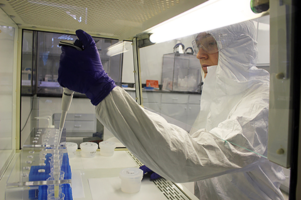 A scientist uses a pipet in a fume hood