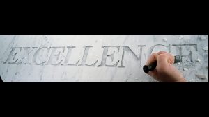 an unfinished carving of the word excellence